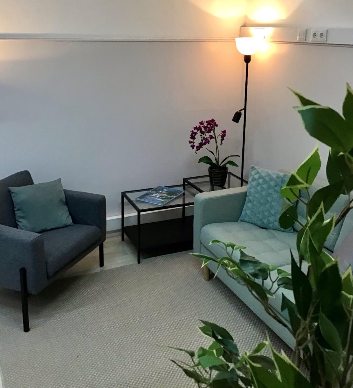 O consultório na Fundação Bomfim: uma poltrona, um sofá, uma mesa de vidro com uma orquídea e um candeeiro aceso.